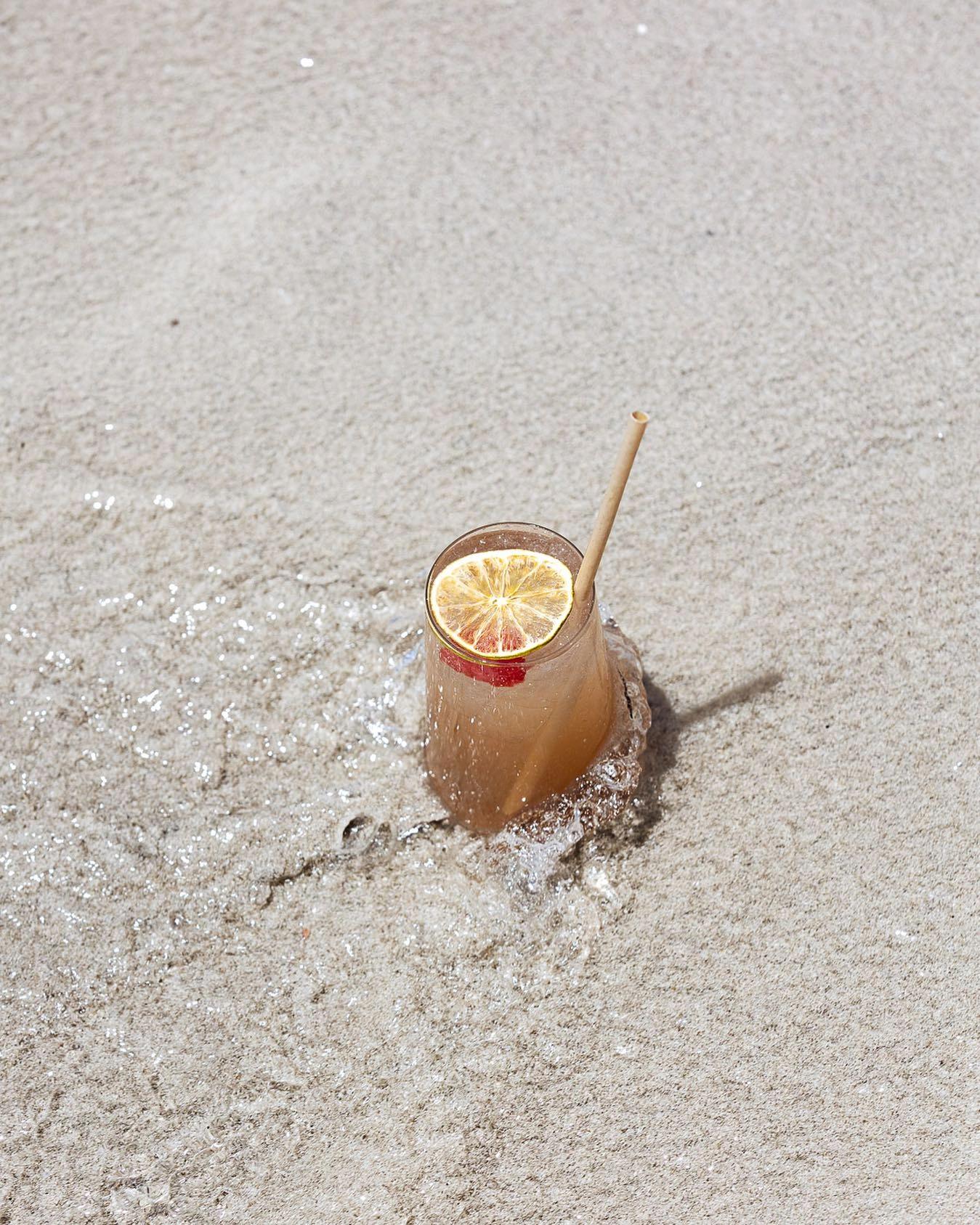 Un cocktail tropical avec glaçons et tranche de citron sur le sable blanc d'une plage