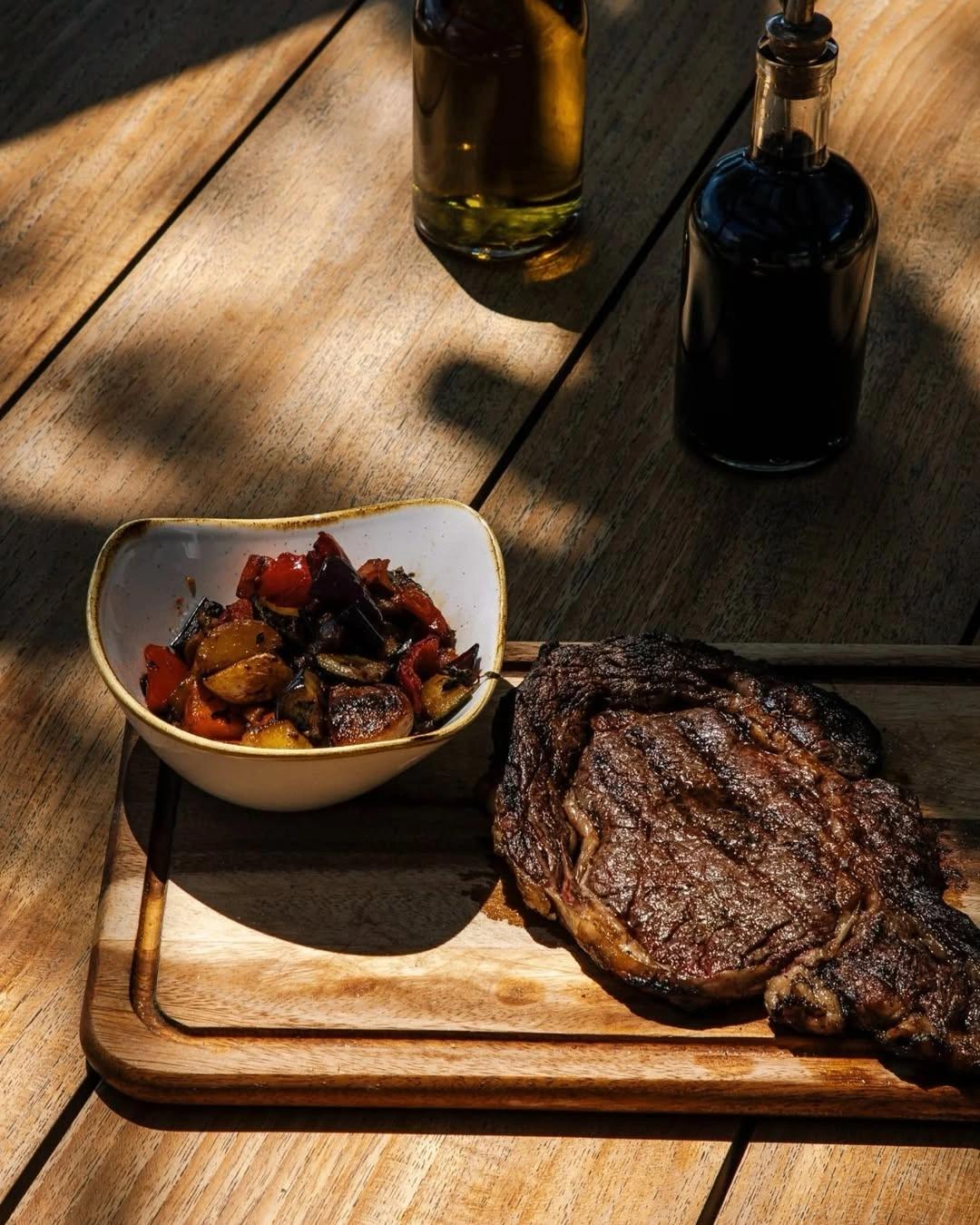 Steak grillé avec légumes rôtis et vins sur la carte du restaurant de plage à Santa Giulia