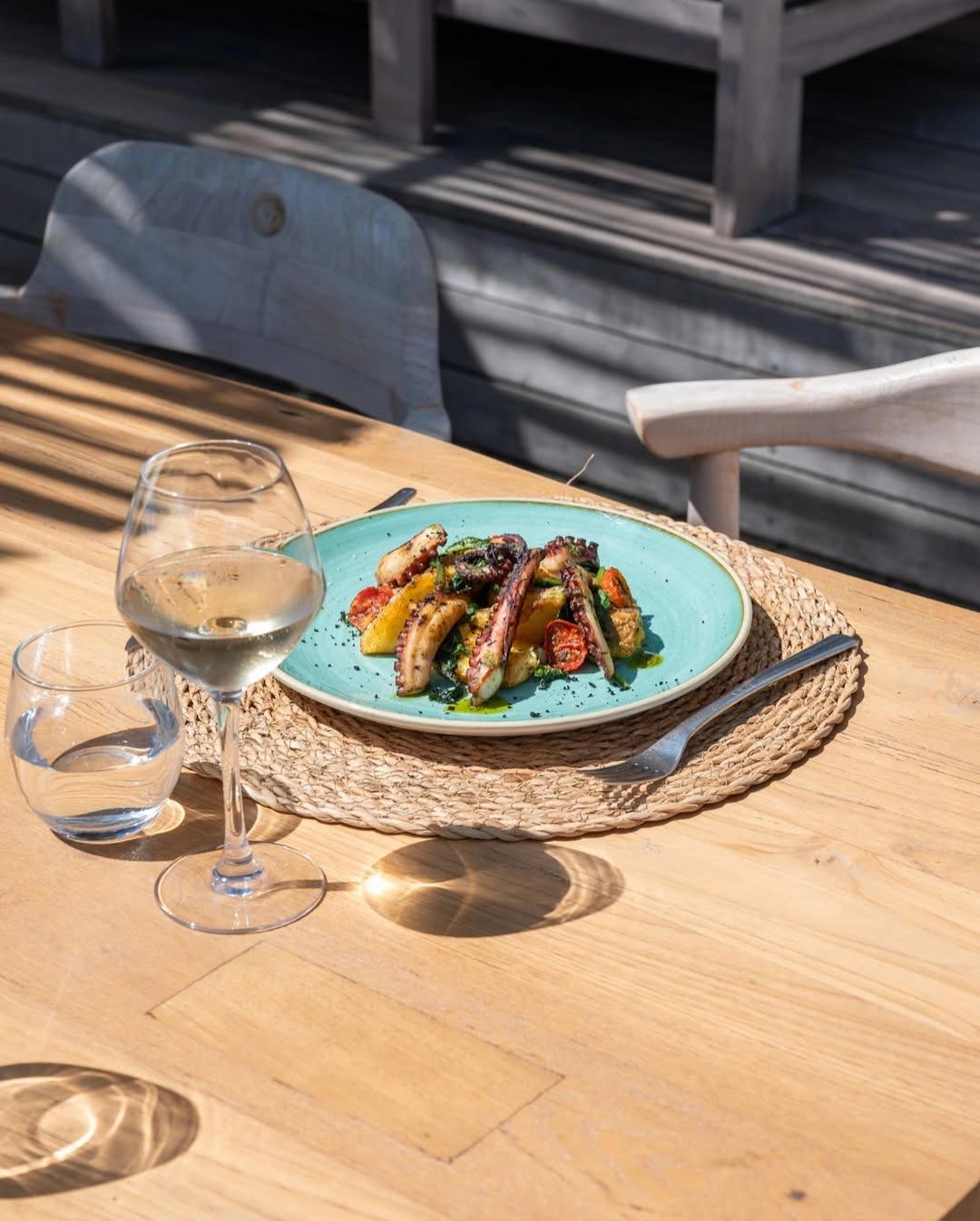 Restaurant de plage à Santa Giulia avec assiette de viande grillée et verre de vin blanc