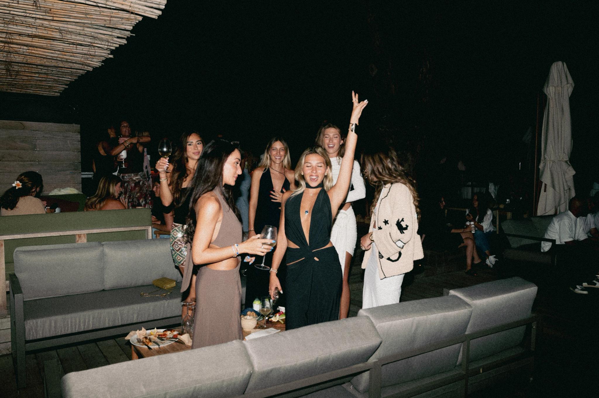 Soirée festive au restaurant de plage à Santa Giulia avec groupe de femmes célébrant