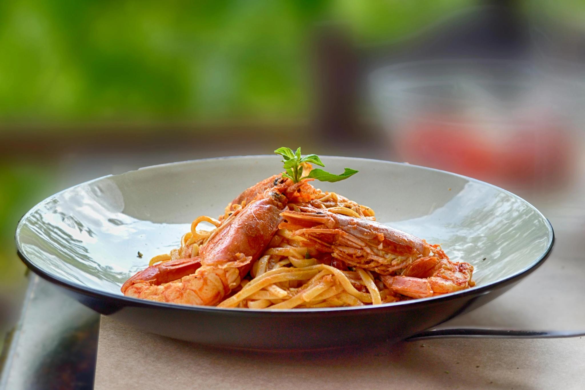 Assiette de pâtes aux fruits de mer avec crevettes et sauce tomate, plat de la carte du restaurant de plage à Santa Giulia