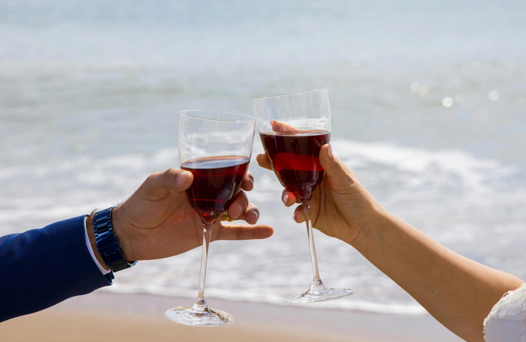 Deux verres de vin rouge levés sur la plage de Santa Giulia lors d'une célébration en bord de mer