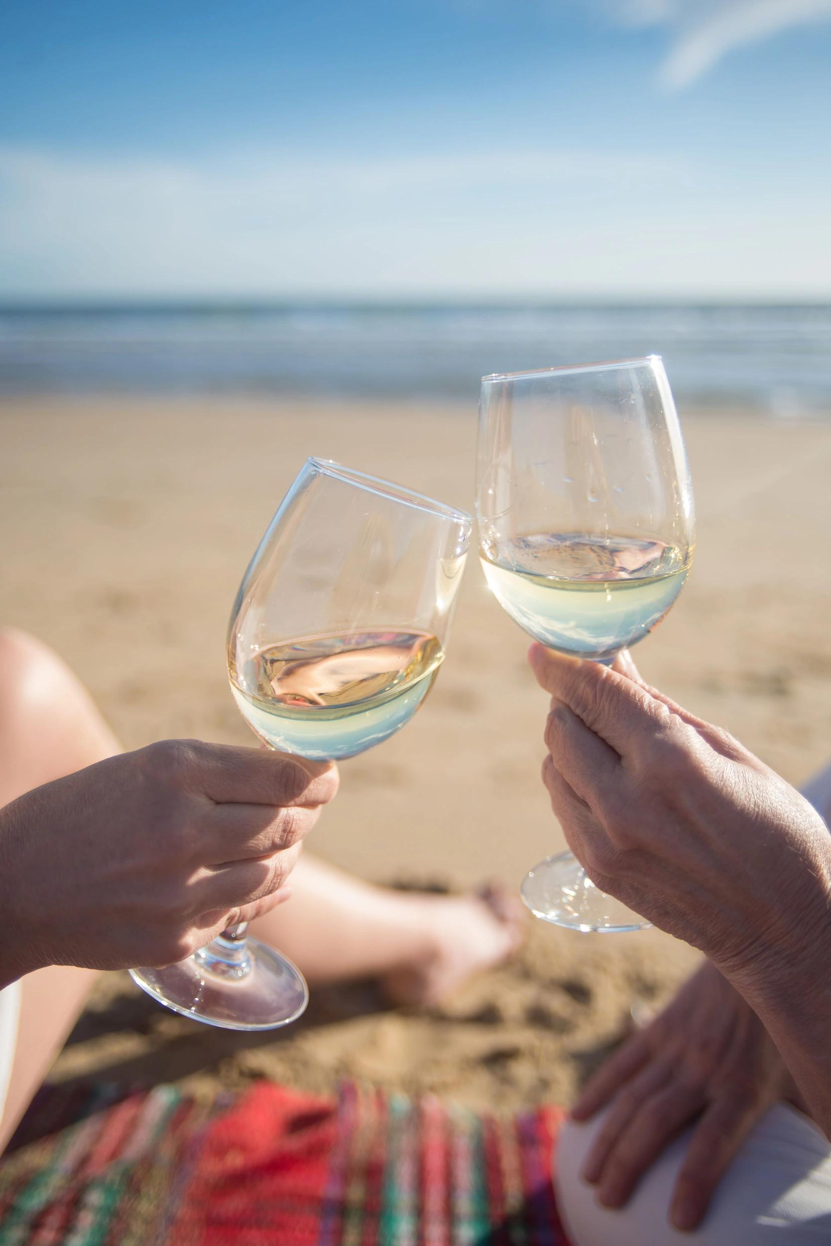 Deux verres de vin blanc levés à la plage de Santa Giulia pour célébrer