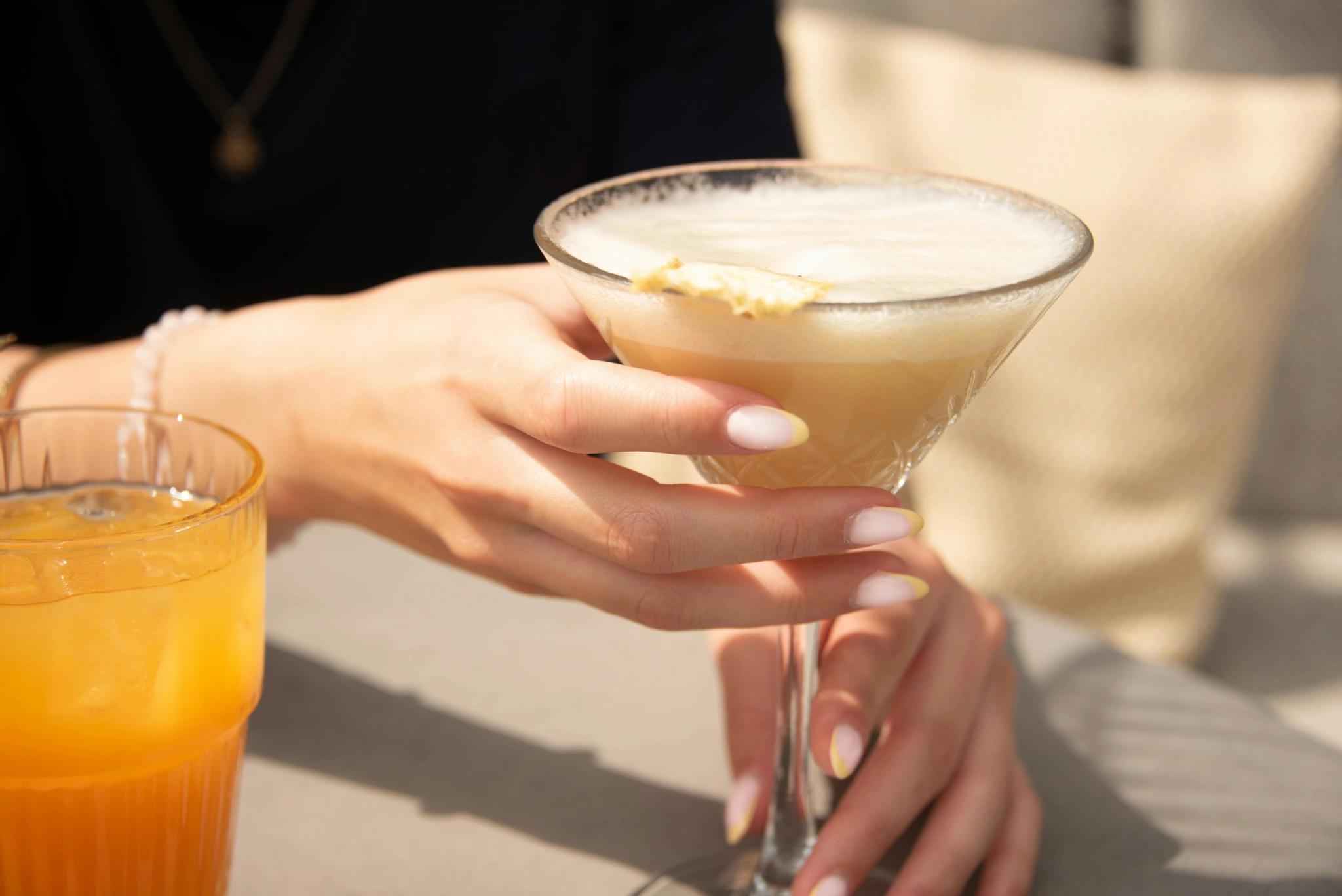 Une femme tenant un verre de cocktail à la carte du restaurant de plage à Santa Giulia