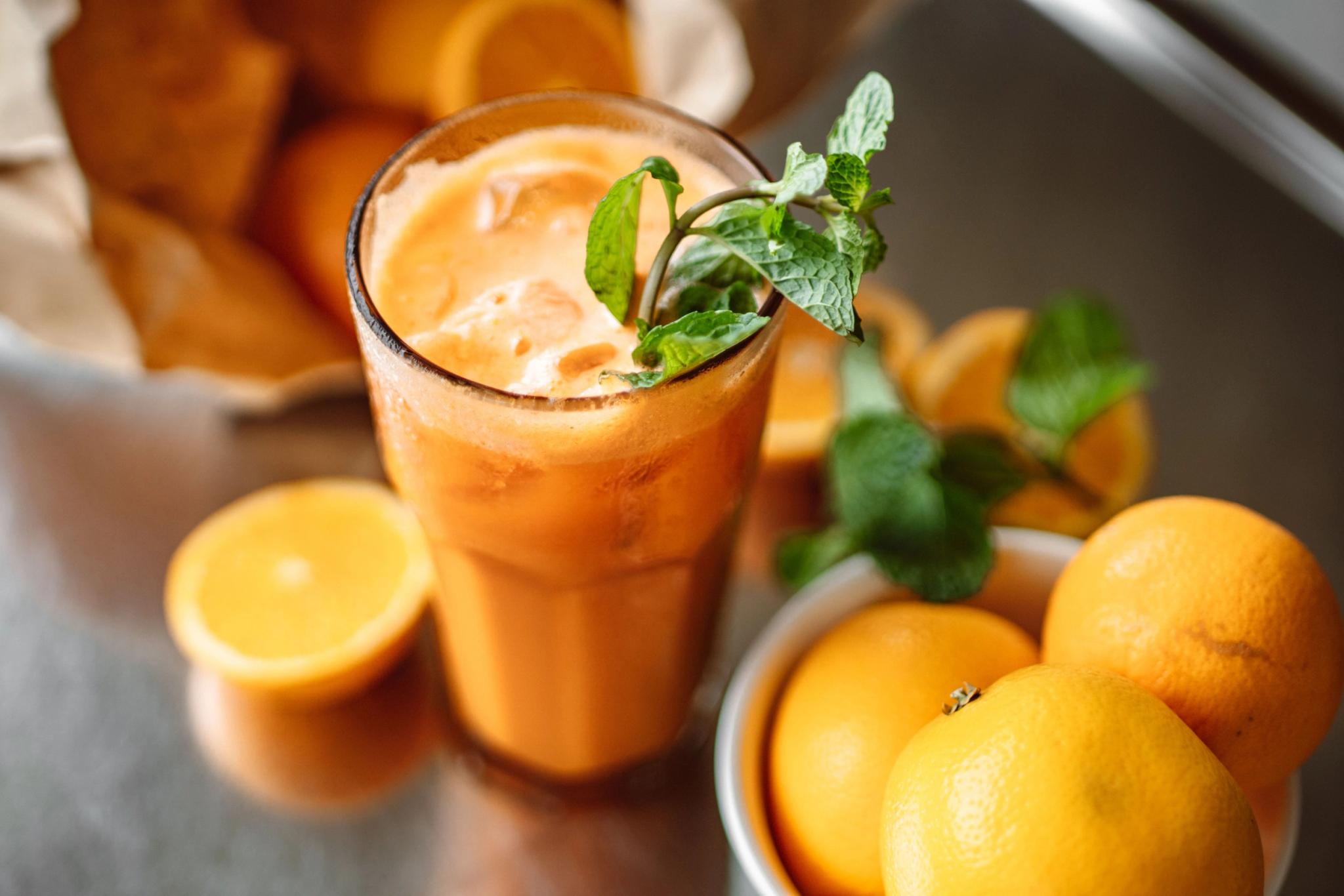 Verre de cocktail orange frais garni de menthe avec citrons frais à côté sur la carte du restaurant de plage à Santa Giulia
