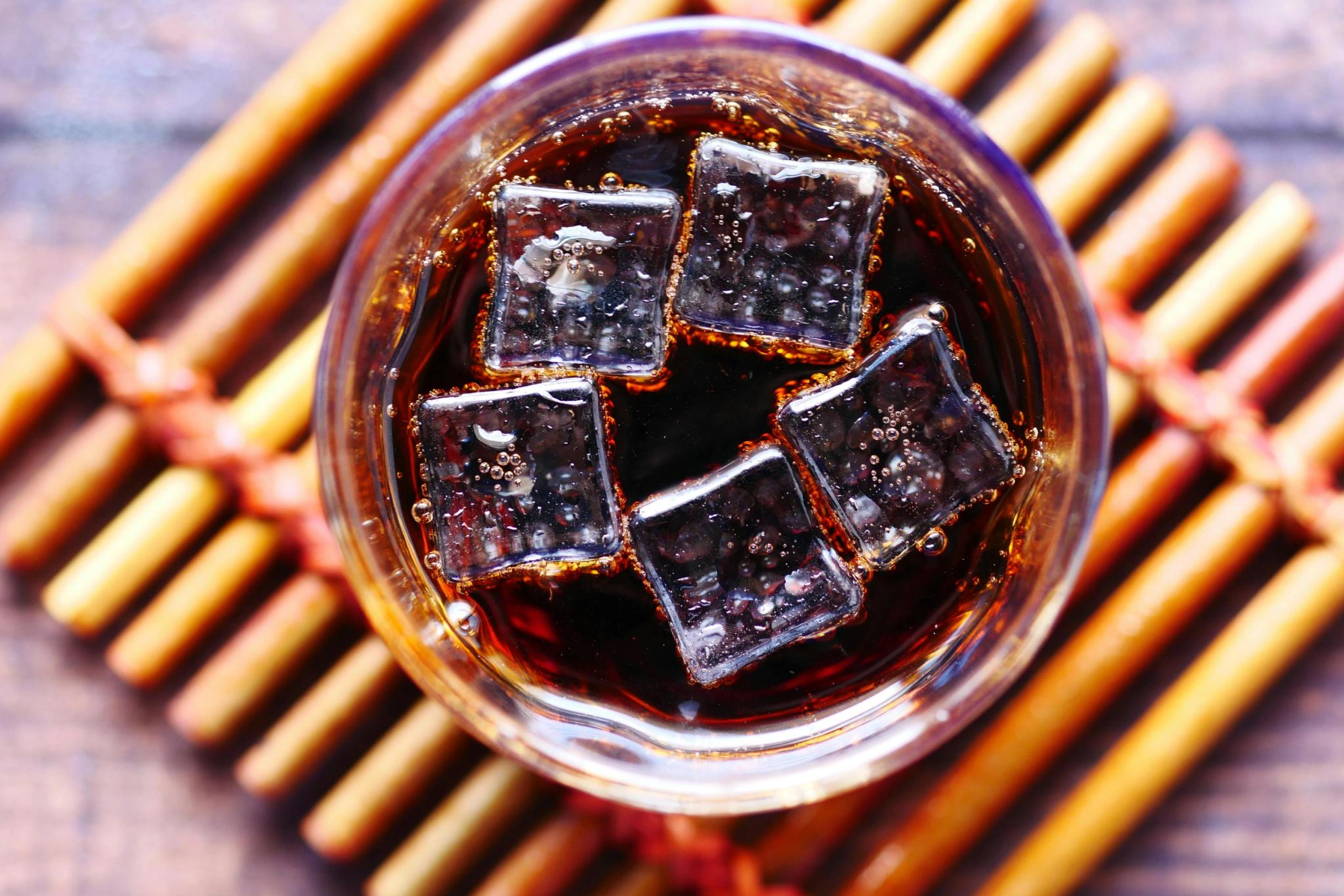 Verre de cola avec glaçons sur napperon rayé doré